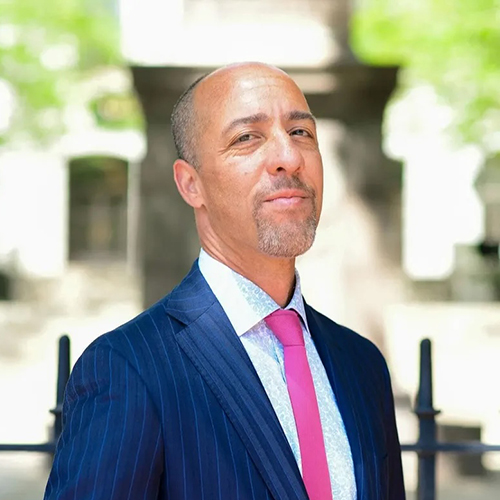 A photo of Dan Delaney in a blue suit and pink tie.