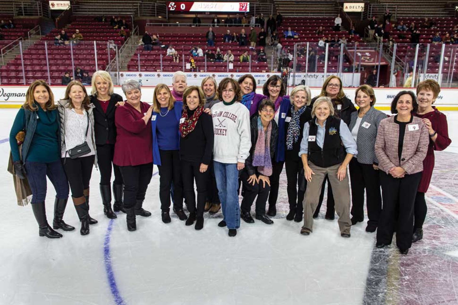 Group photo of former BC women's hockey players on center ice in Conte Forum