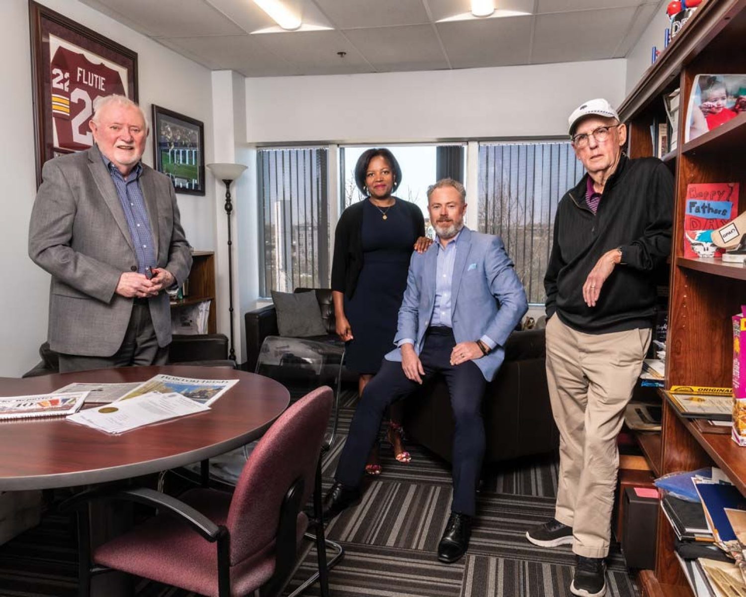 Dorchester Reporter founder Ed Forry ’69, copublisher Linda Dorcena Forry ’96, executive editor Bill Forry ’95, and associate editor Tom Mulvoy ’64 photographed in Bill Forry's office.