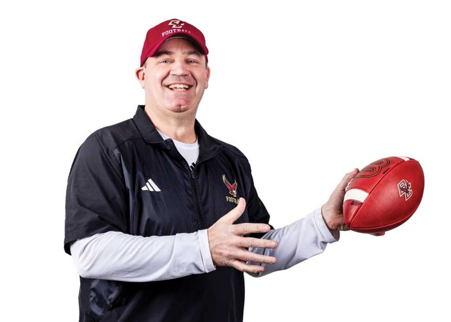 Coach Bill O'Brien laughing and holding a football.