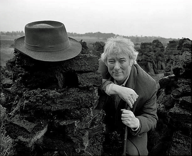 Seamus Heaney at a turf bog in Bellaghy with his father’s coat, hat, and walking stick, 1986