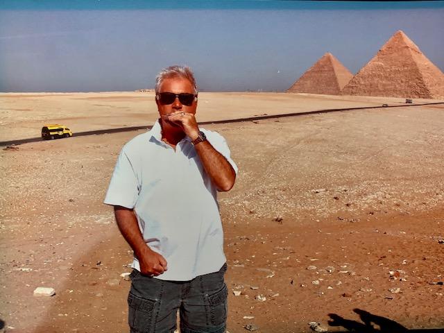 Carl Lanzilli playing harmonica in front of Eqyptian pyramids