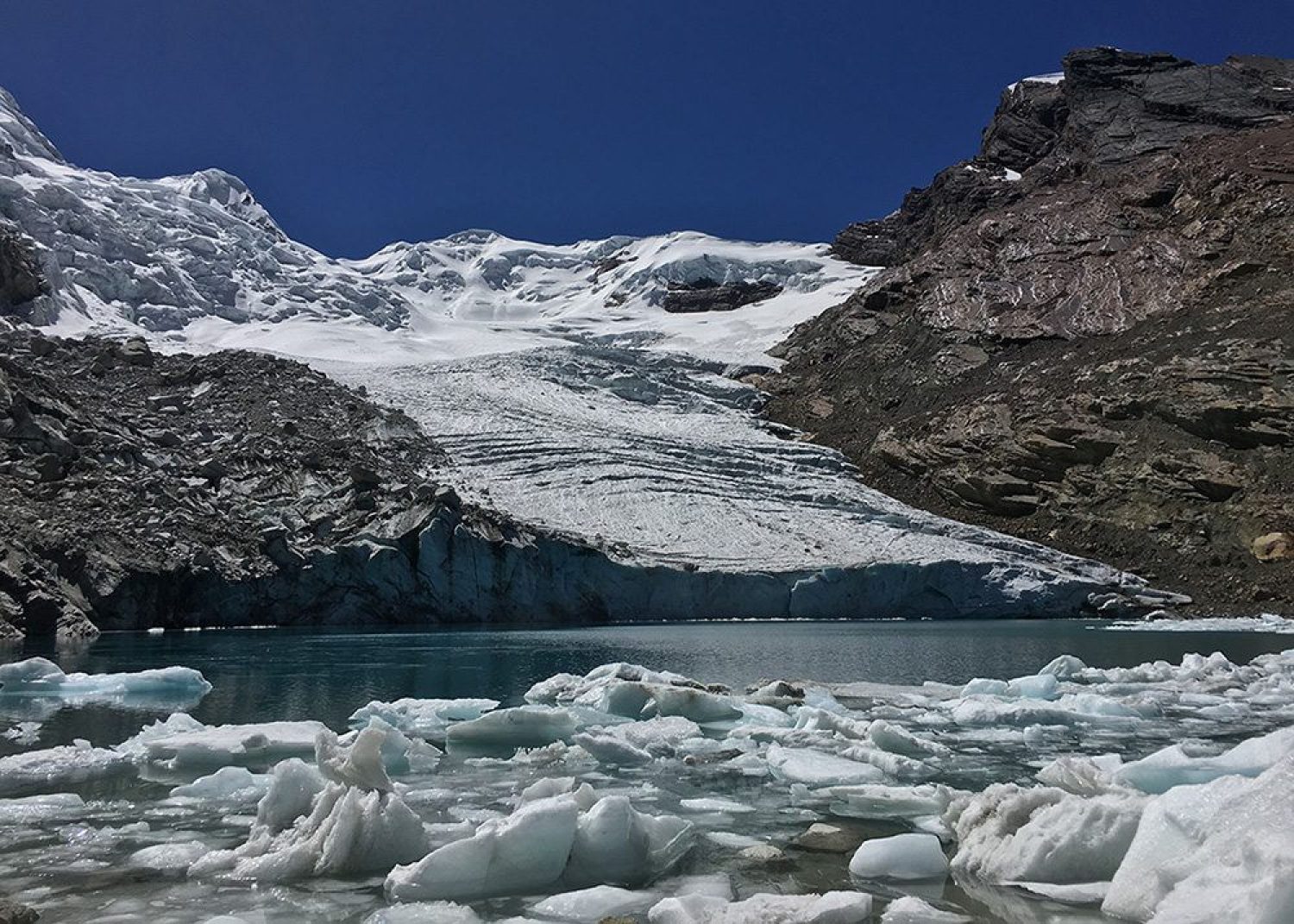 Snow covered mountains behind melted glacial ice