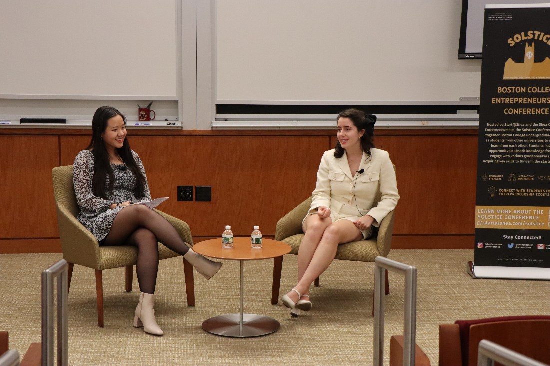 Two women doing a panel discussion during  the Solstice conference. They are sitting in chairs talking to one another, in front of an auditorium full of attentive students.