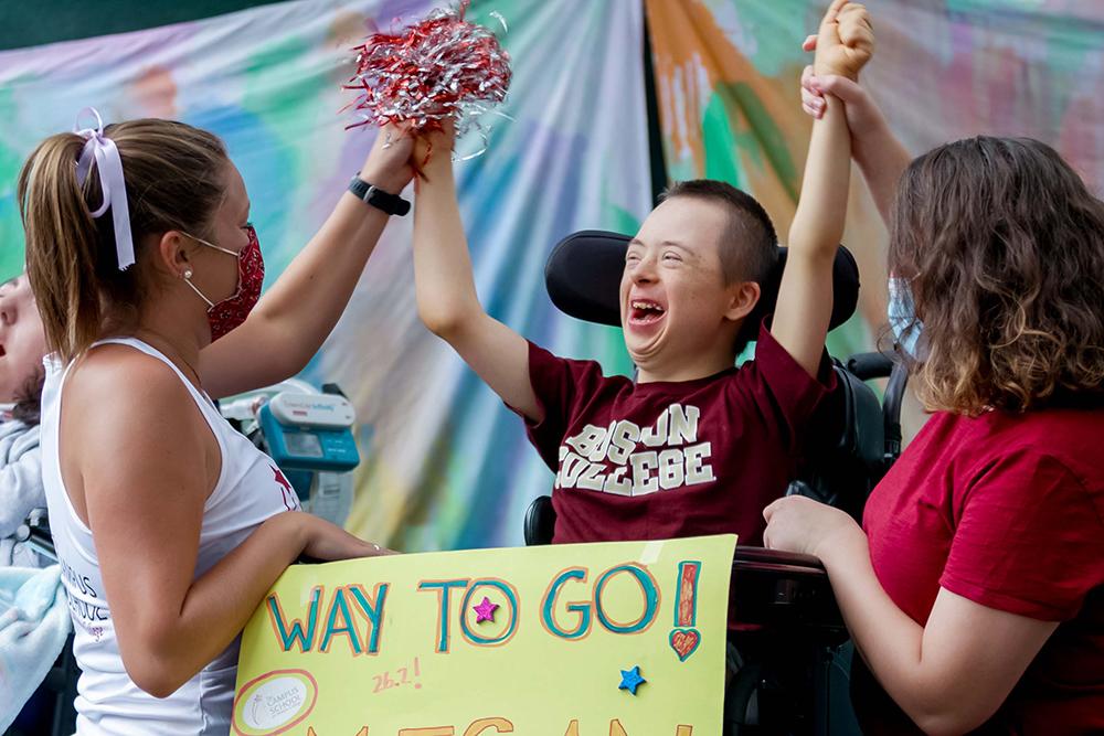 A student cheering while raising both arms in the air