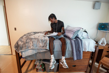 On the first day of orientation, Armand Paul pauses on his bed to review Messina materials.