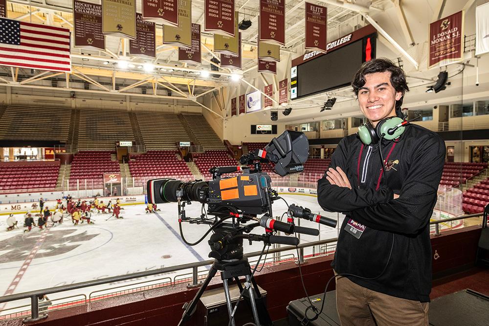 A person standing next to a camera in a hockey rink