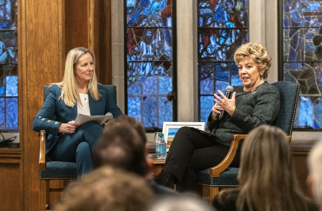 two women in conversation in front of a stained glass window